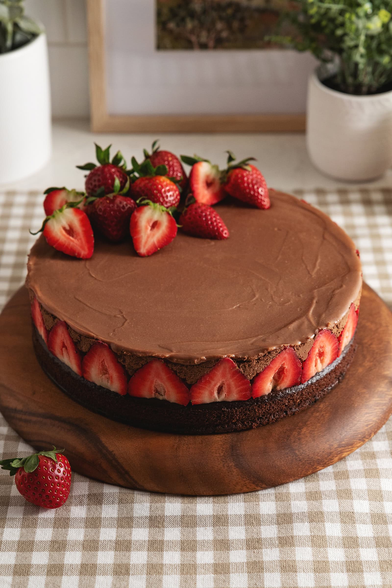 A chocolate mousse cake with strawberries lining the sides of the cake and on top of the cake.