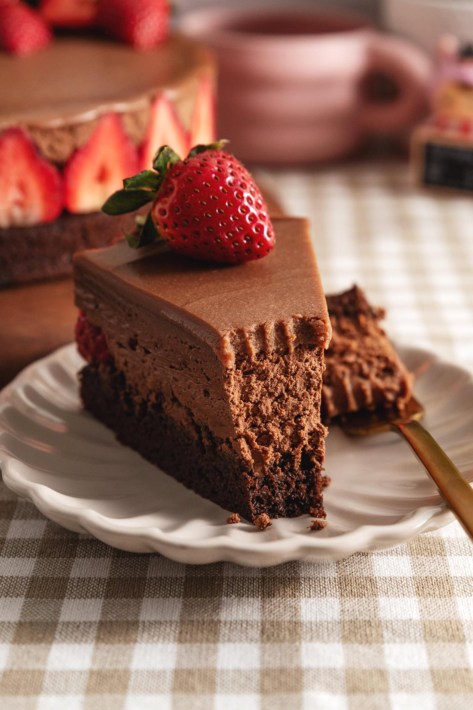 A slice of chocolate mousse cake with a forkful taken out of it to show the texture inside.