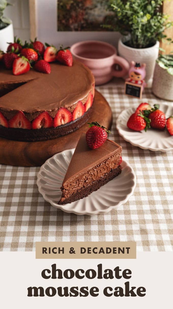 A slice of chocolate mousse cake on a plate in front of the rest of the cake.
