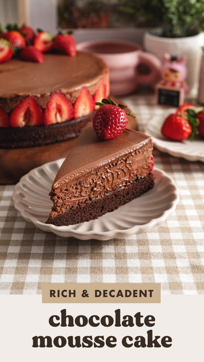 A slice of chocolate mousse cake with a strawberry on top on a plate, showing the three layers of chocolate.
