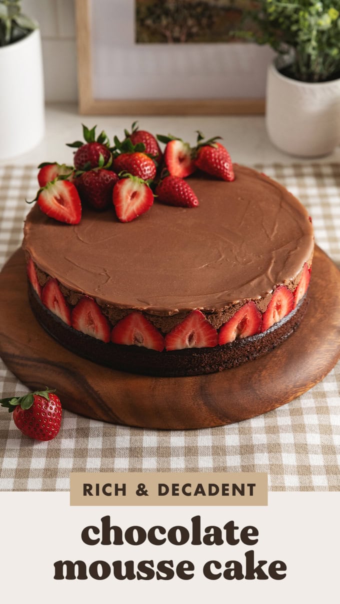 A chocolate mousse cake with strawberries lining the sides of the cake and on top of the cake.