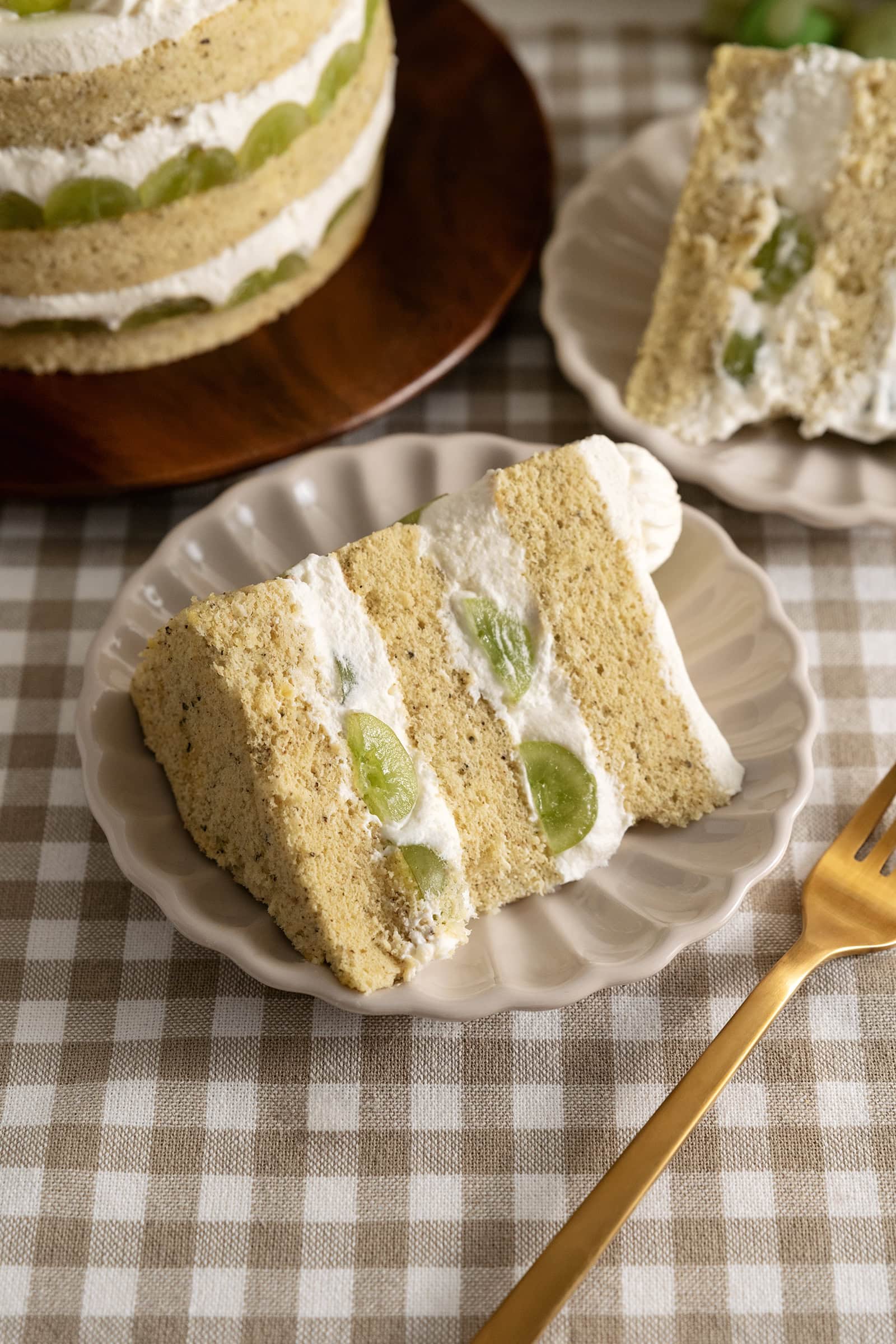 A slice of jasmine green grape cake on a plate next to a fork.
