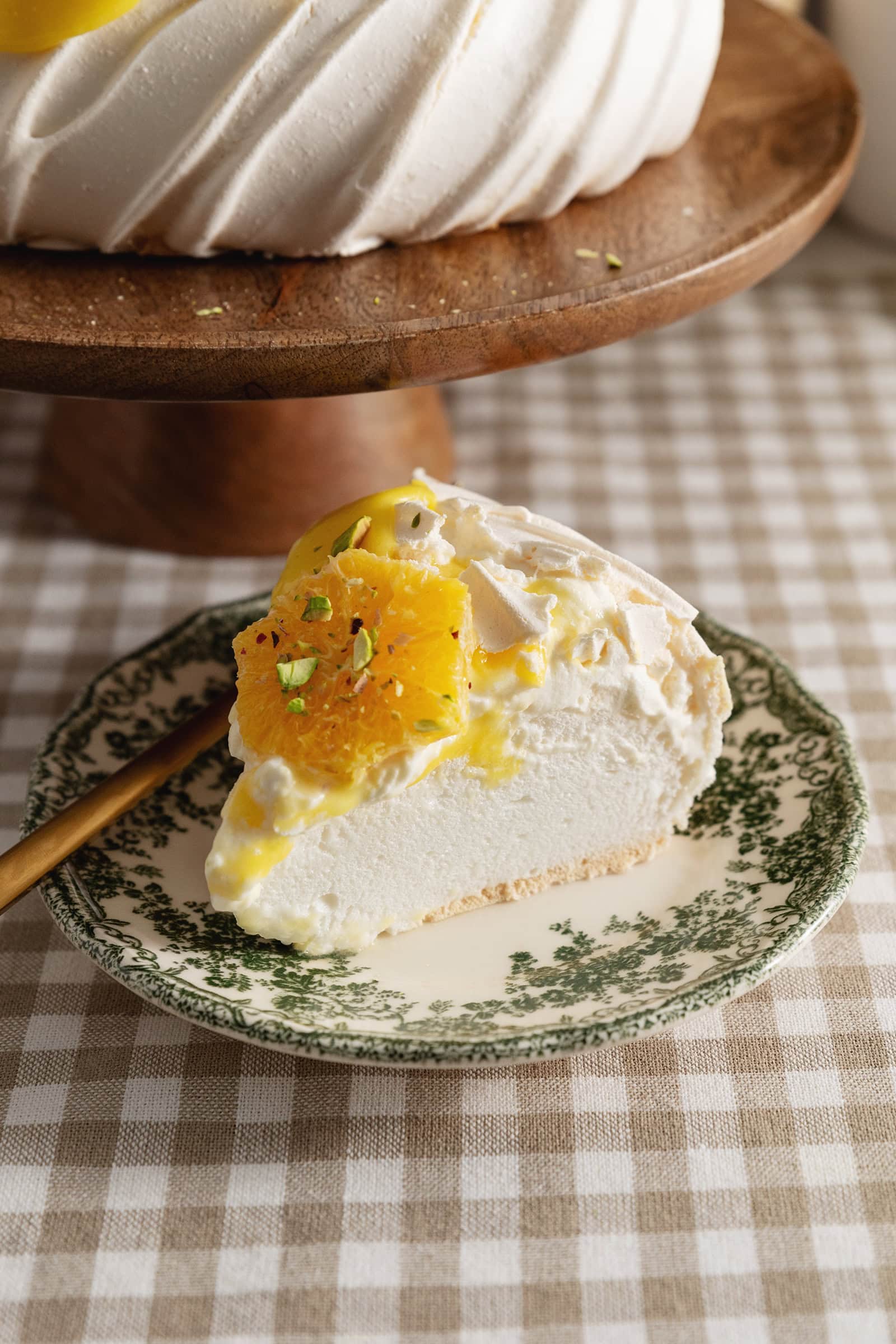 A slice of citrus pavlova on a green vintage plate.