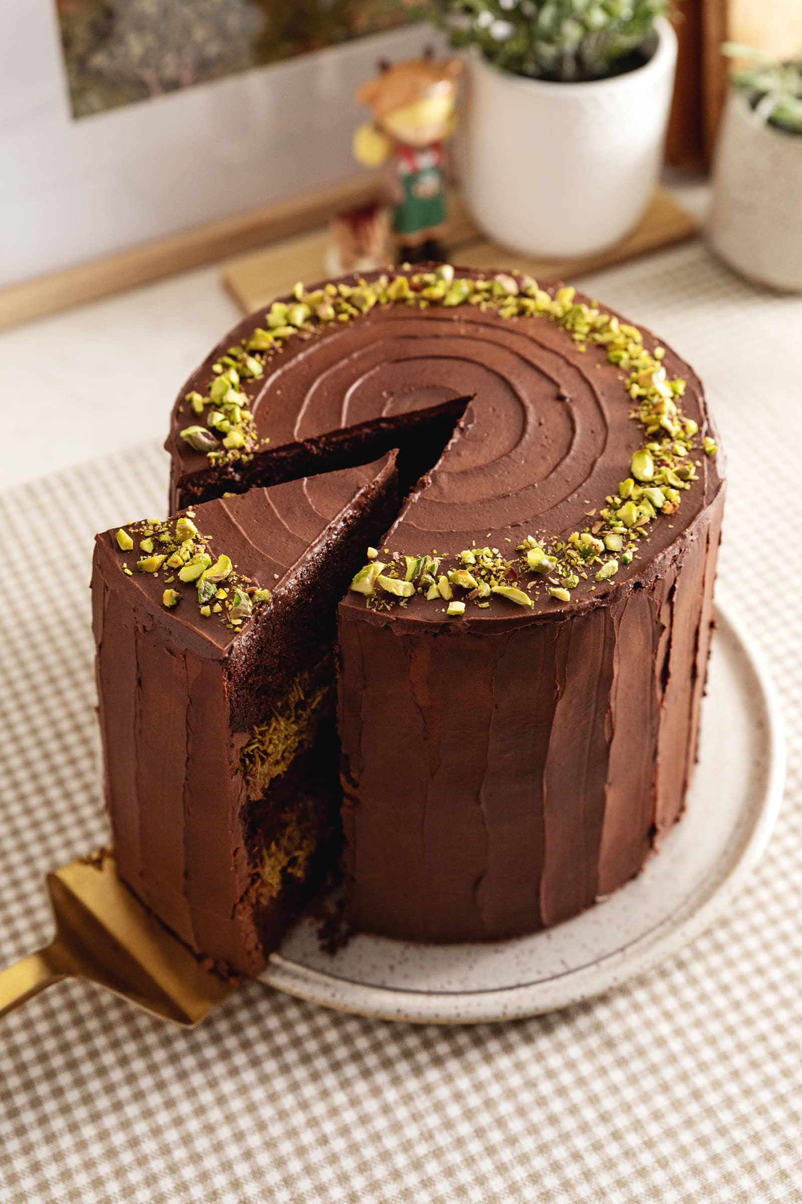 A Dubai chocolate pistachio cake with a slice cut out and slightly pulled out.