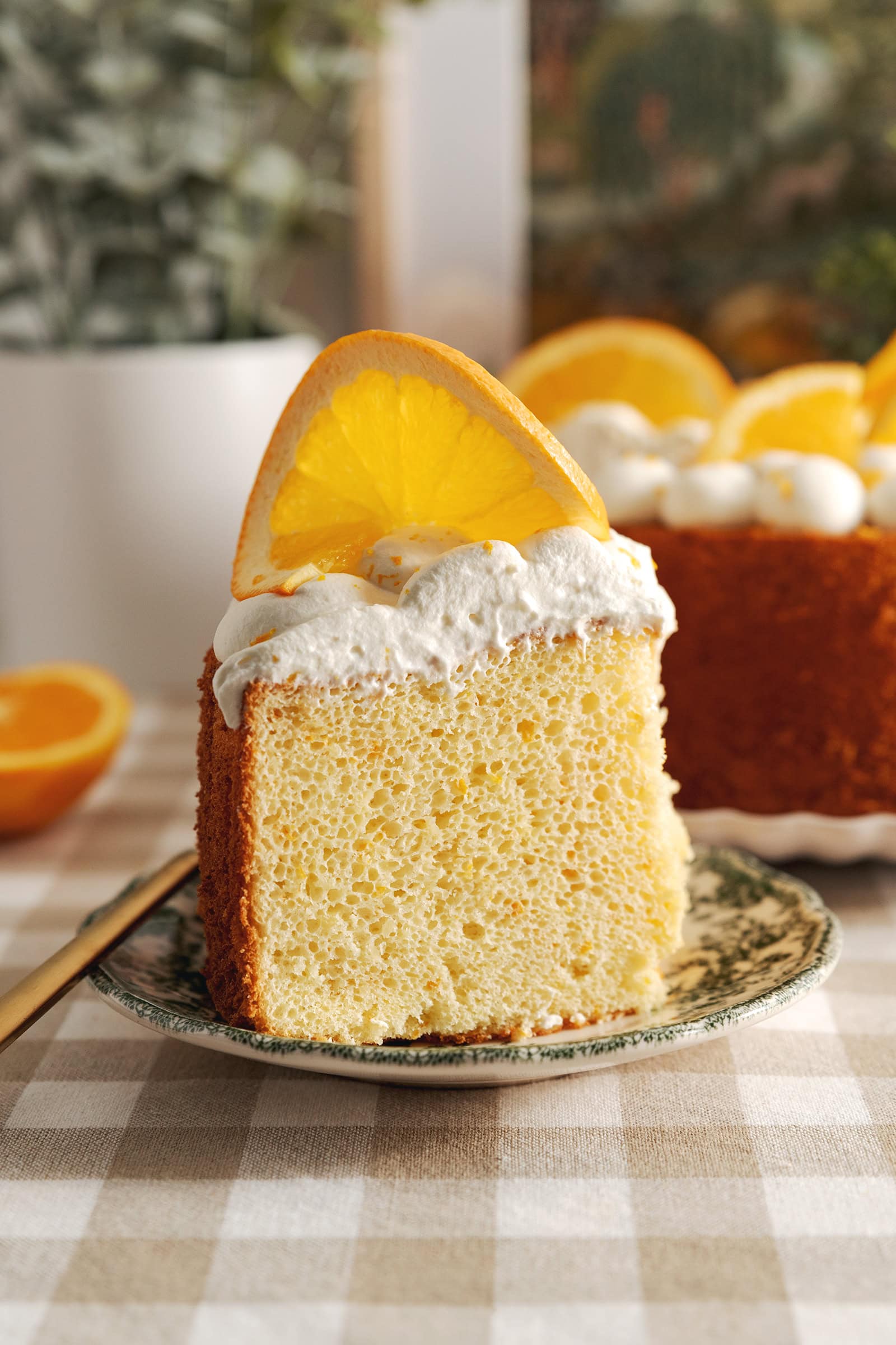 A slice of orange chiffon cake on a plate showing the texture inside.