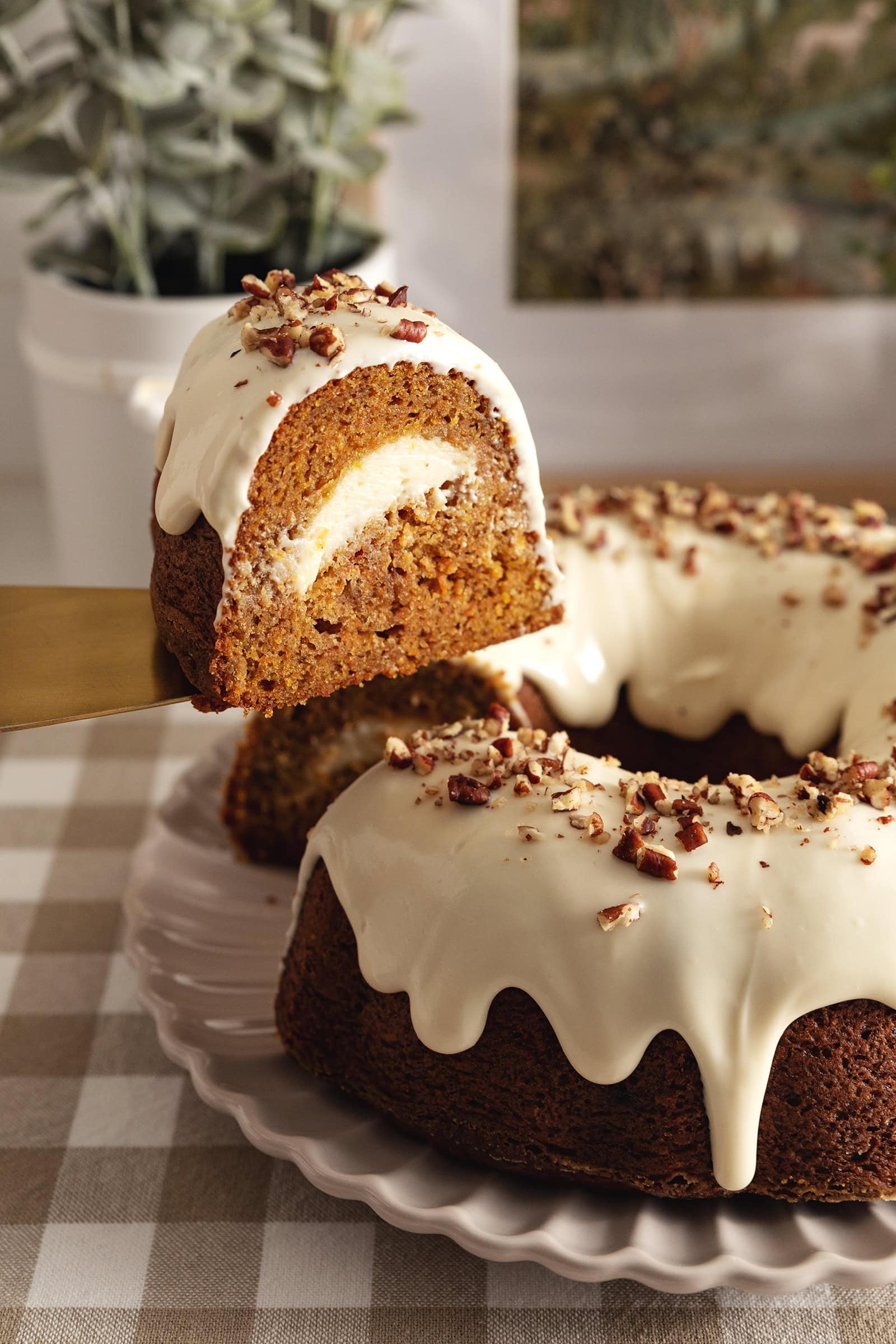 A slice of carrot bundt cake being lifted by a cake server above the rest of the cake.
