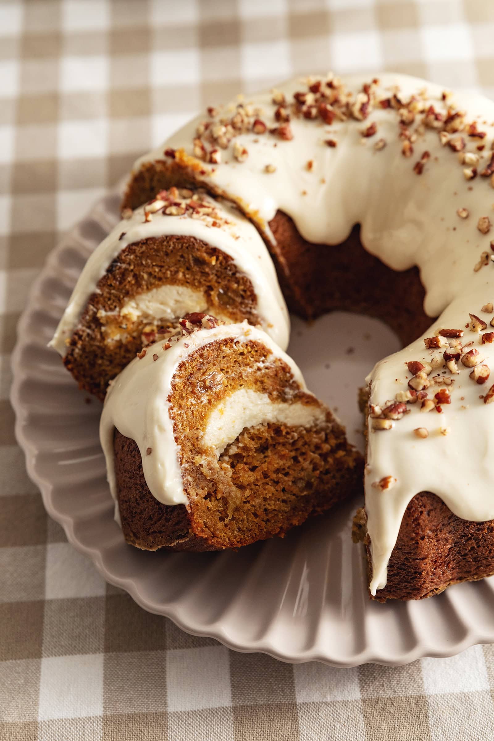 Two slices of carrot bundt cake leaning against each other next to the rest of the cake.