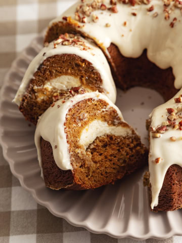 Two slices of carrot bundt cake leaning against each other next to the rest of the cake.