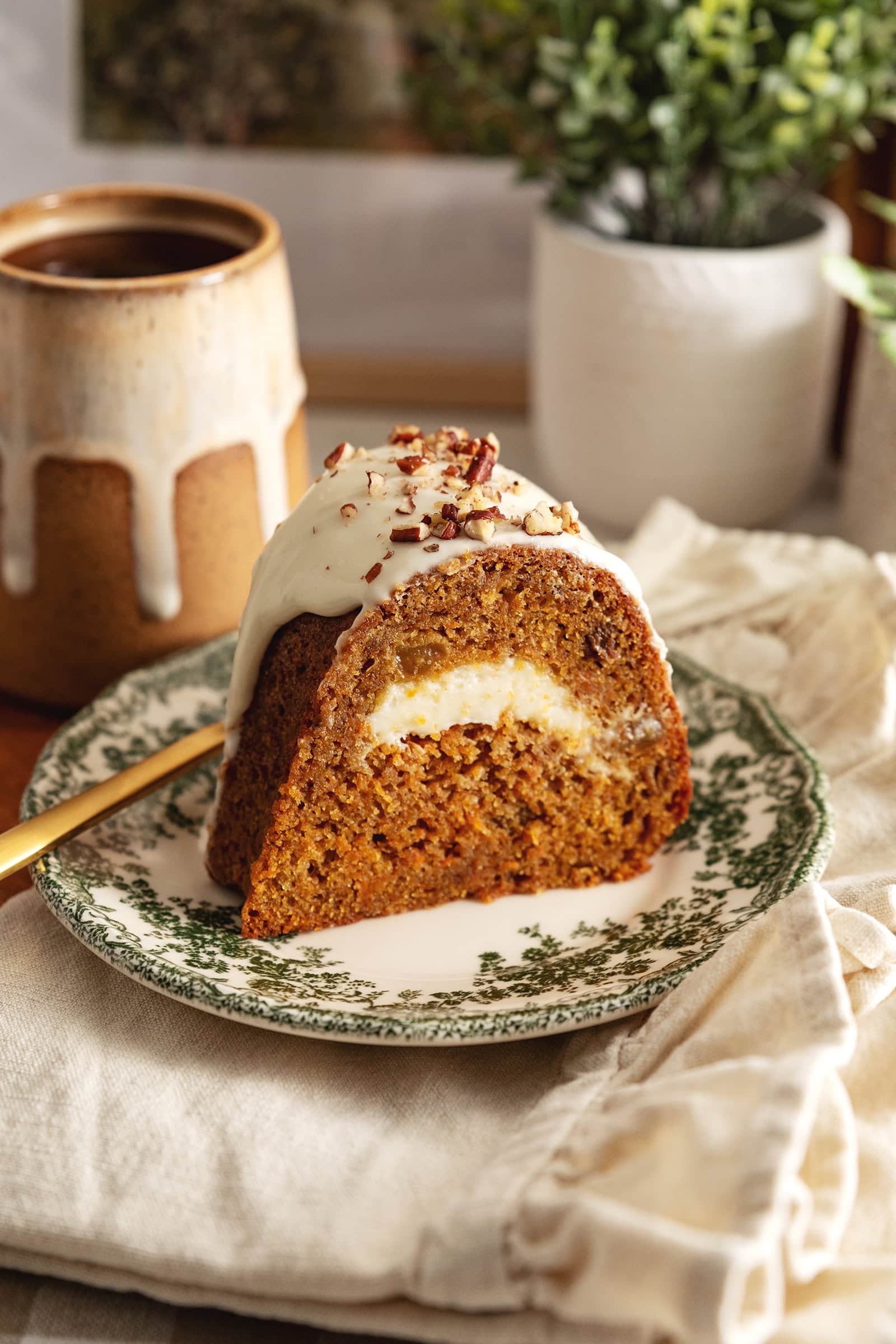 A slice of carrot bundt cake with a swirl of cream cheese in the middle on a green vintage plate.