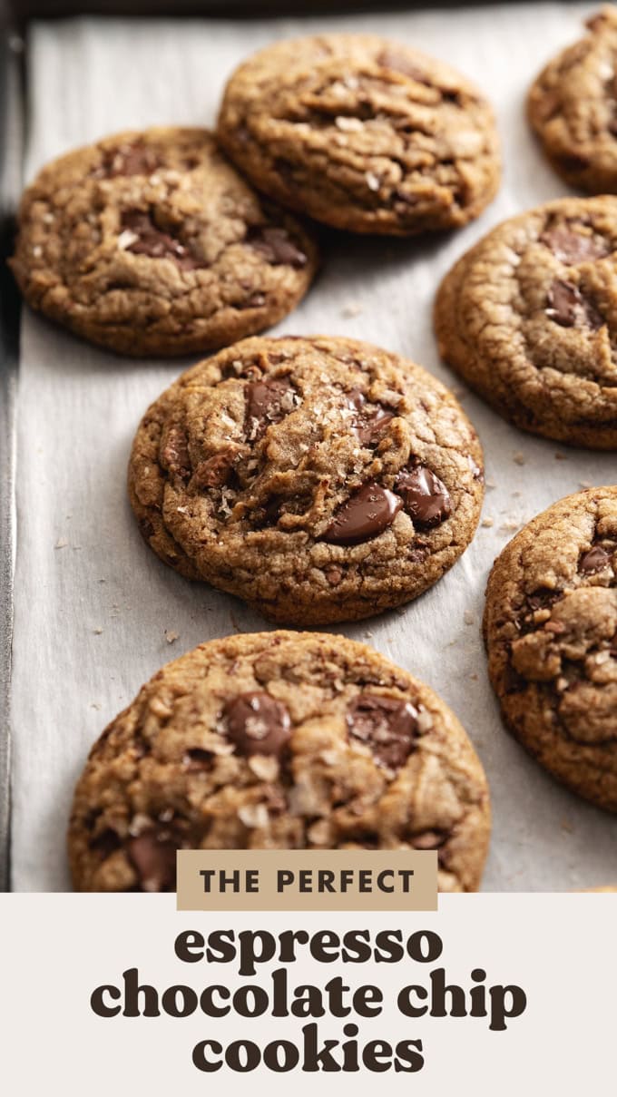 Espresso chocolate chip cookies scattered on parchment paper on a baking tray.