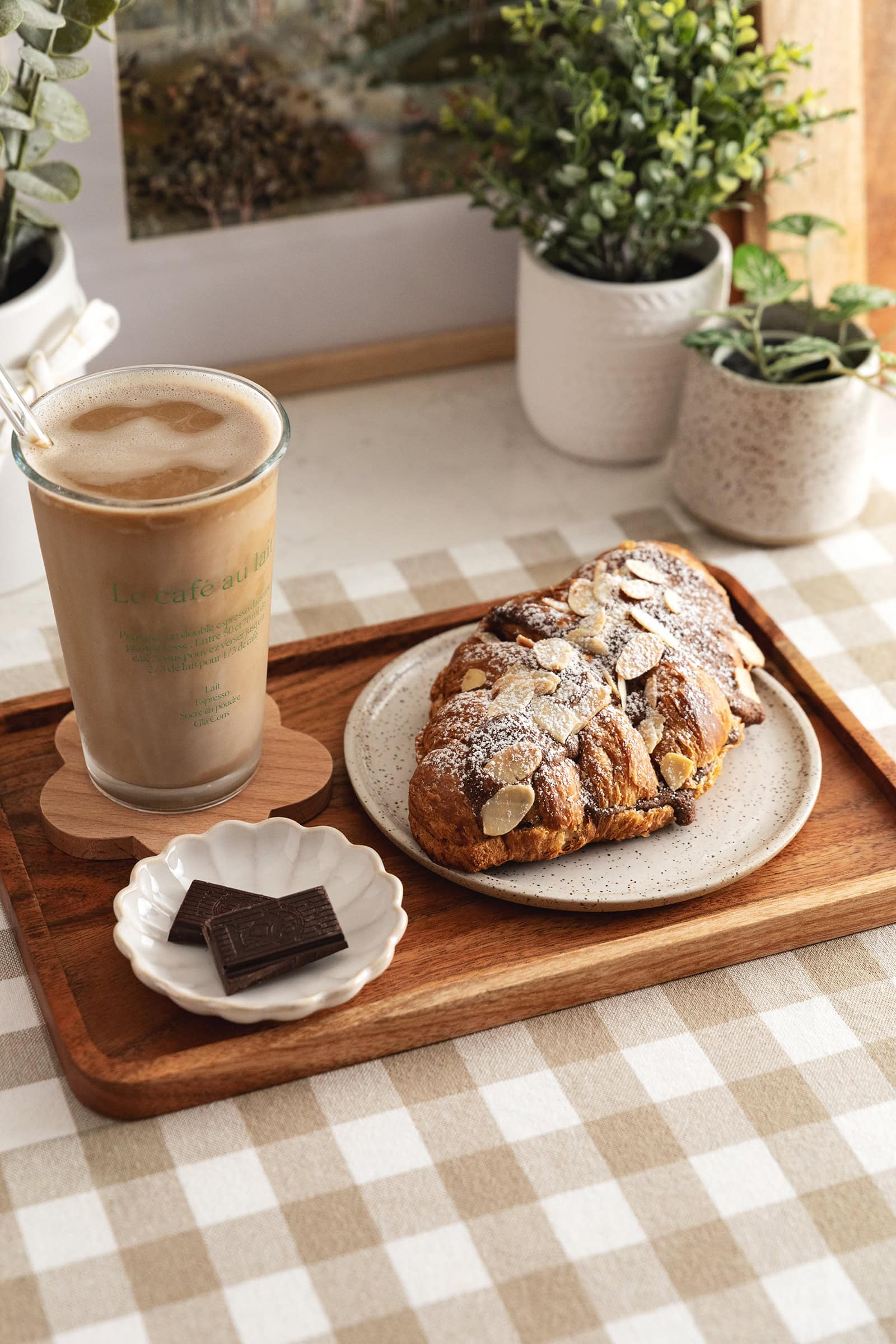 A chocolate almond croissant on a wood serving tray with an iced latte.