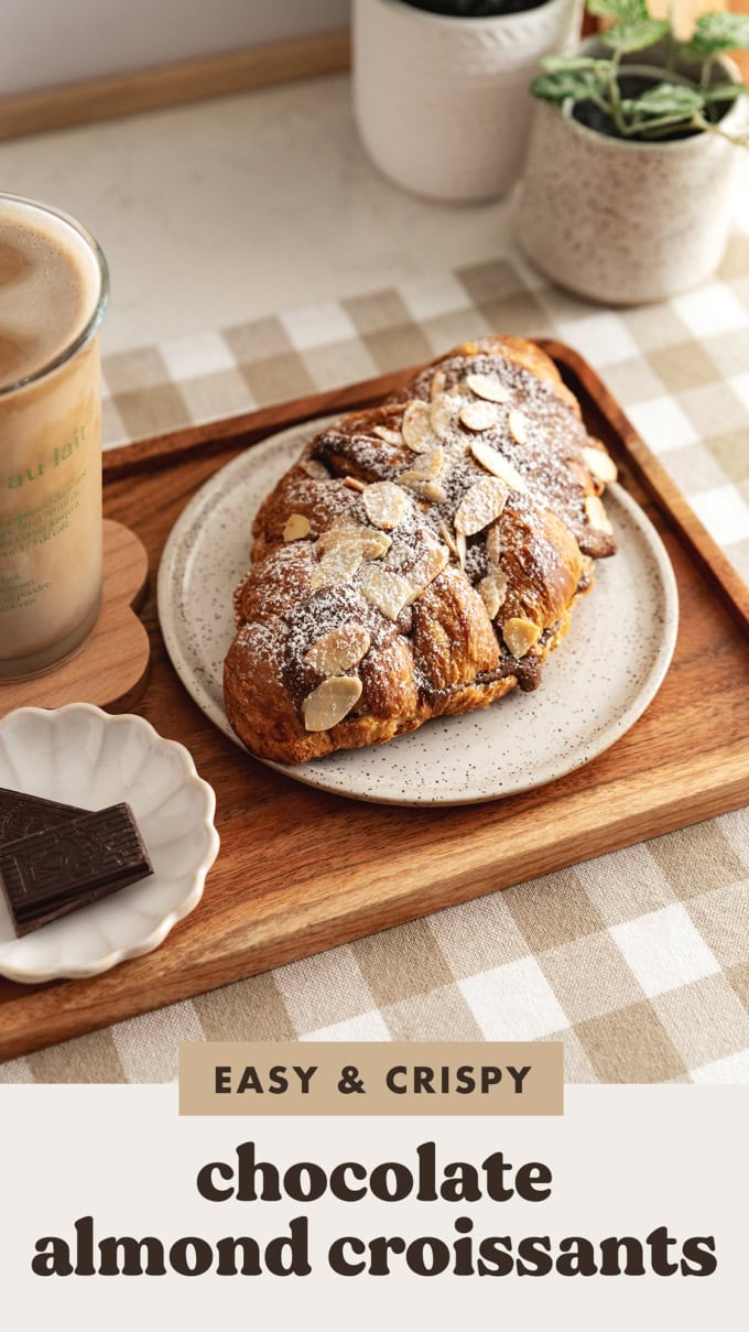 A chocolate almond croissant on a plate on a wood serving tray.