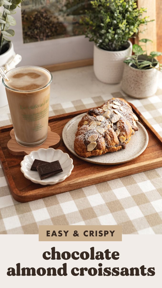 A chocolate almond croissant on a wood serving tray with an iced latte.