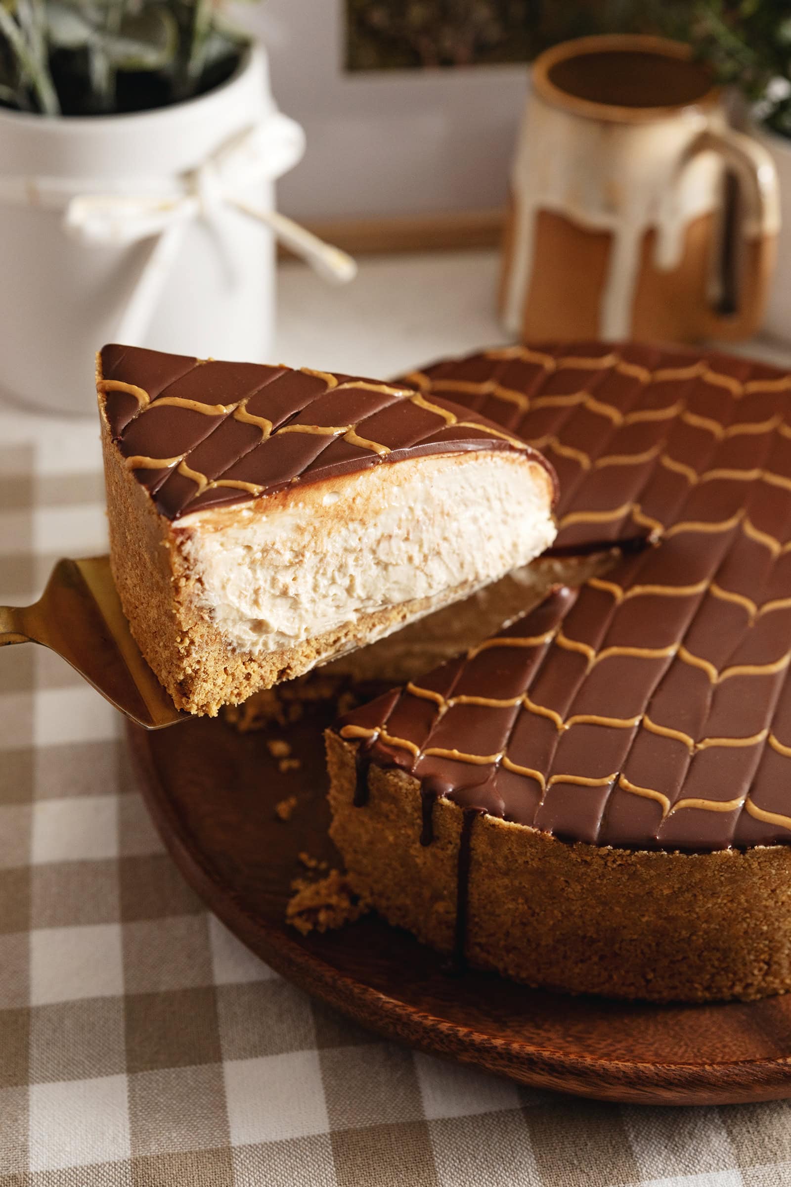 A slice of chocolate peanut butter cheesecake being lifted above the rest of the cake with a cake server.