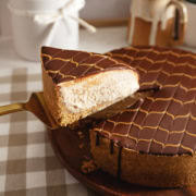 A slice of chocolate peanut butter cheesecake being lifted above the rest of the cake with a cake server.