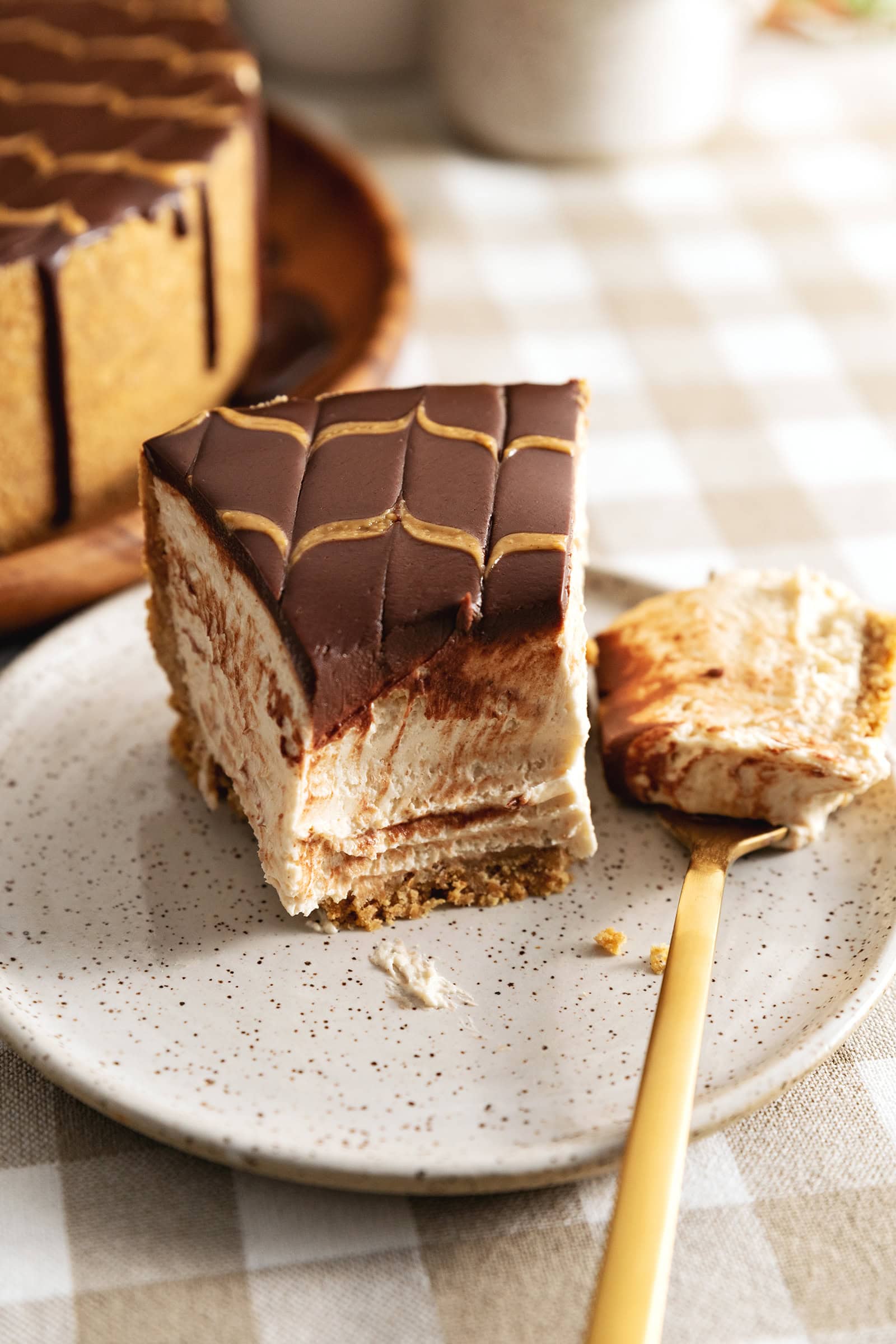 A slice of chocolate peanut butter cheesecake on a plate with a forkful of cheesecake resting next to it.