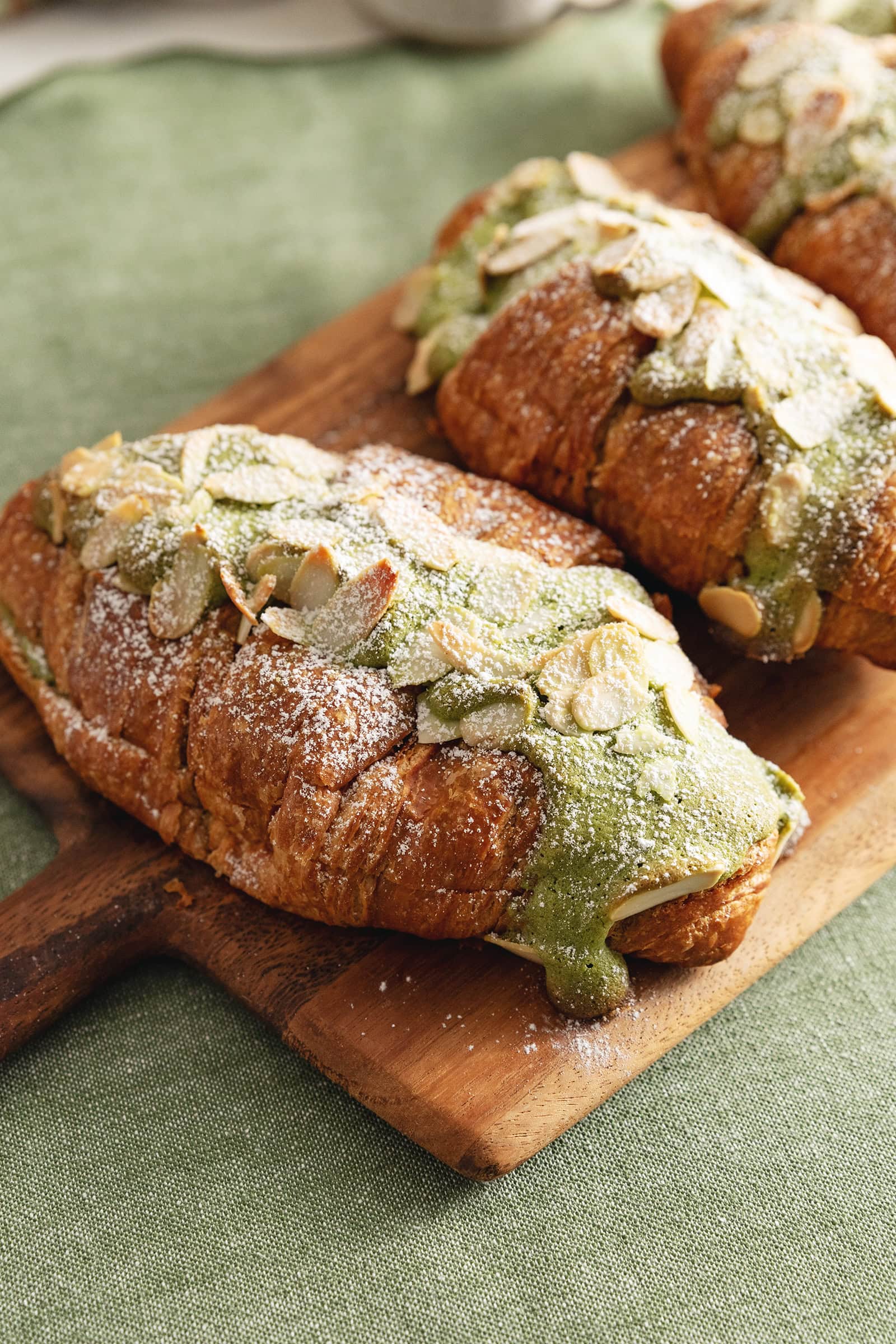 Close-up of a matcha almond croissants with matcha frangipane dripping down the side.