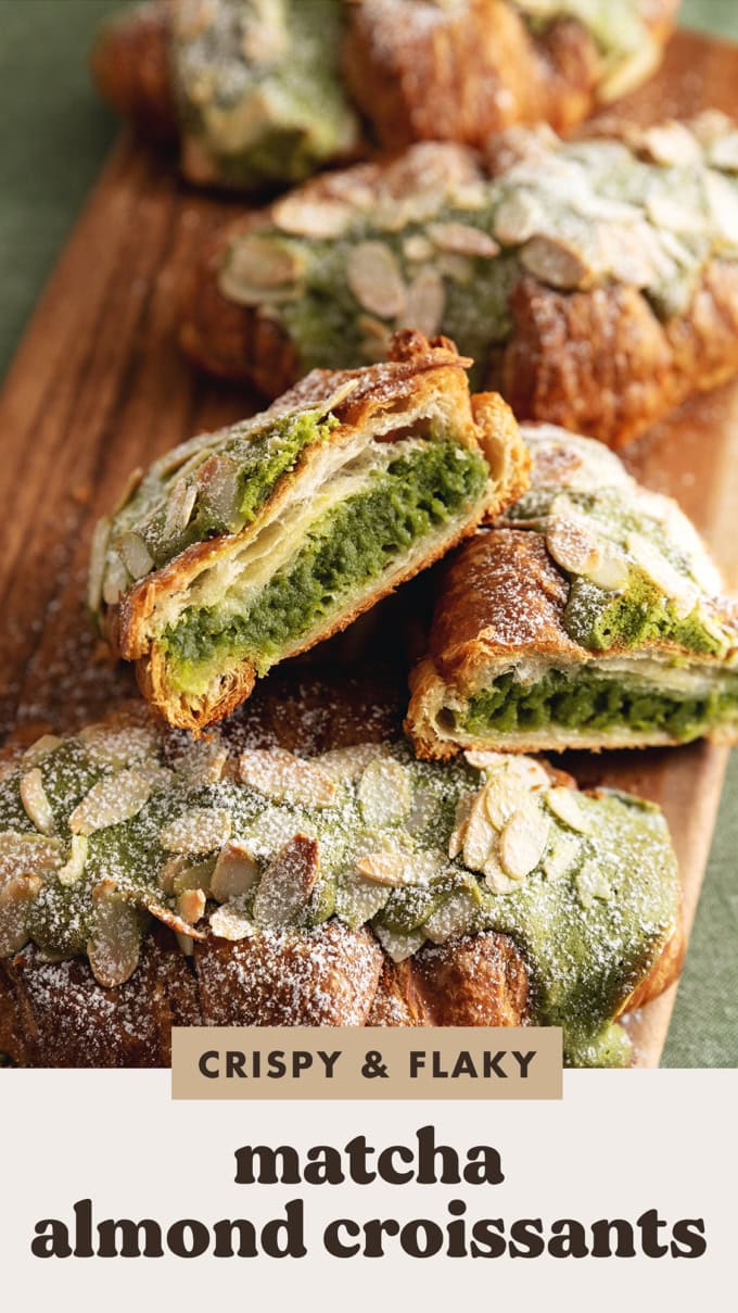A matcha almond croissant cut in half to show the filling inside resting against other whole almond croissants.