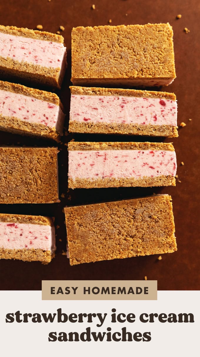 Strawberry ice cream sandwiches lined up on a wooden board showing the layers of ice cream and crust.