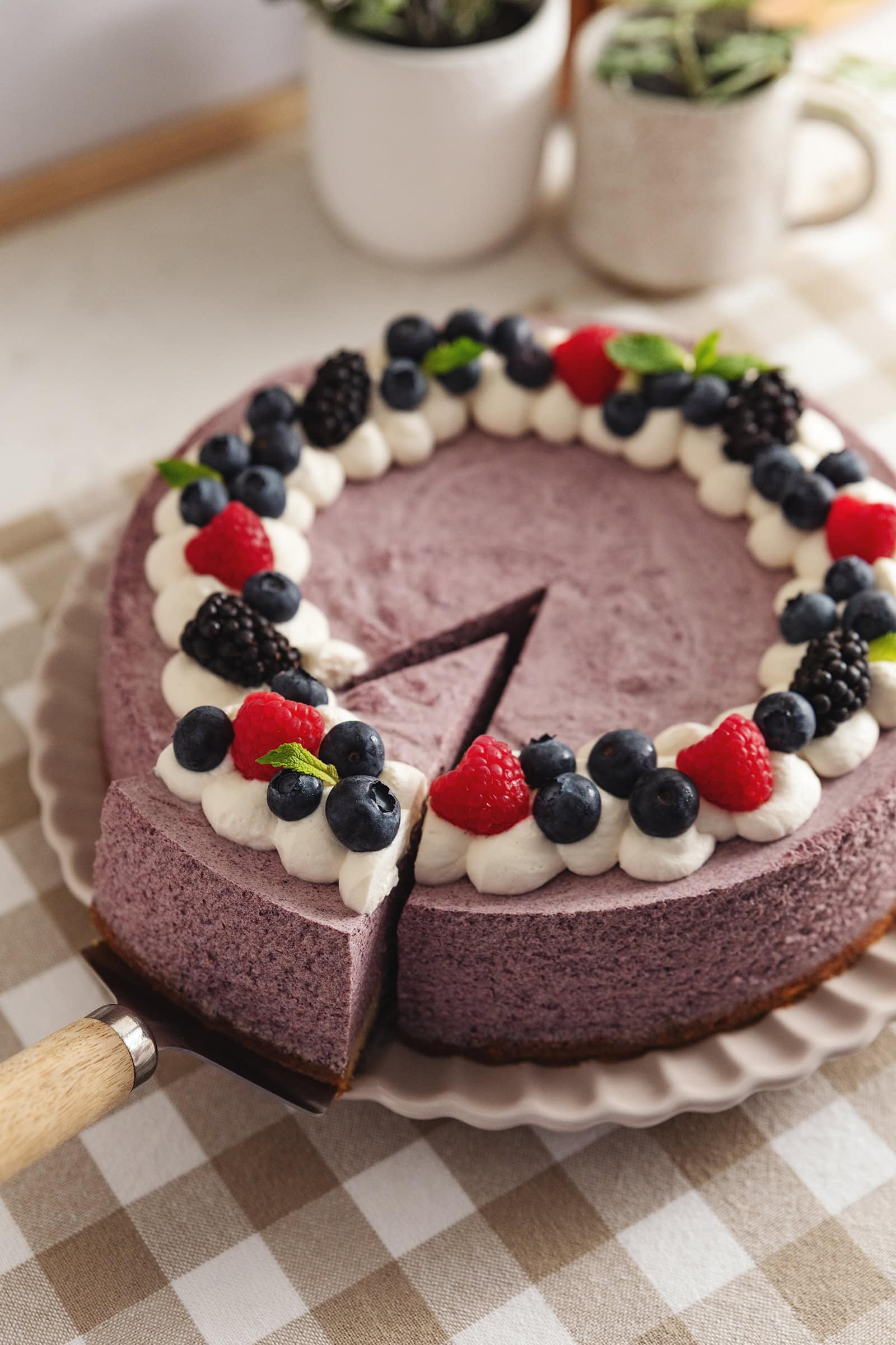 A blueberry mousse cake with a slice cut out of it and pulled slightly out from the rest of the cake.