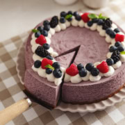A blueberry mousse cake with a slice cut out of it and pulled slightly out from the rest of the cake.