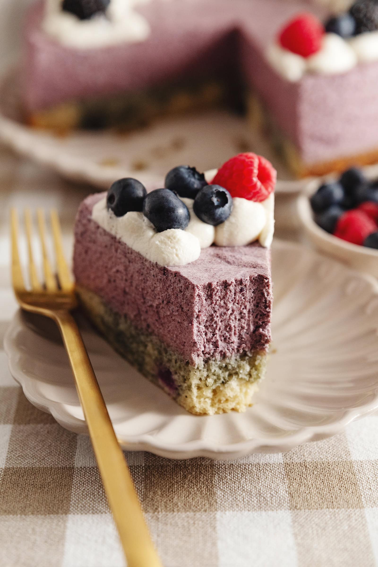 A slice of blueberry mousse cake with a forkful taken out of it to show the airy mousse texture.