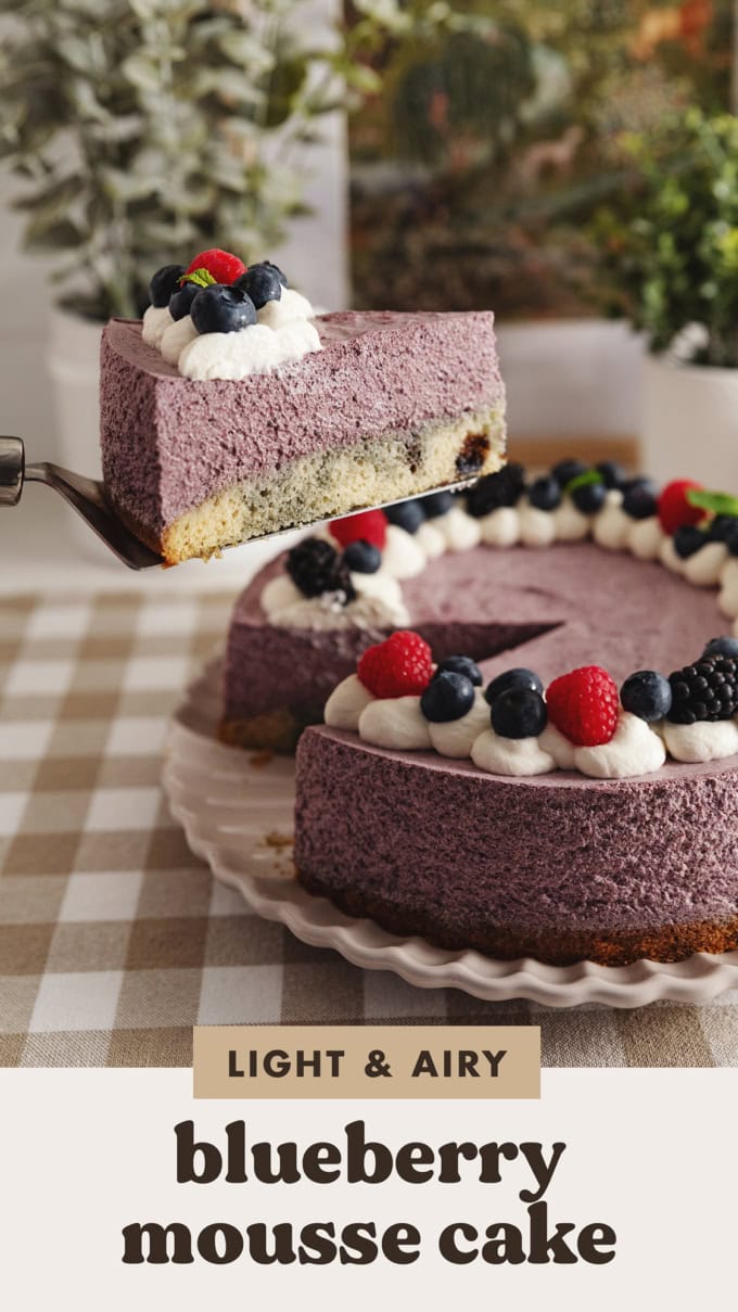 Lifting a slice of blueberry mousse cake above the rest of the cake with a cake server.