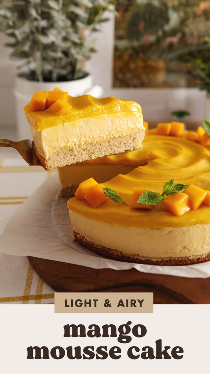 A slice of mango mousse cake being lifted above the rest of the cake to show the layers.