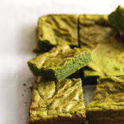 Close-up of a matcha brownie rest on other brownies on parchment paper.