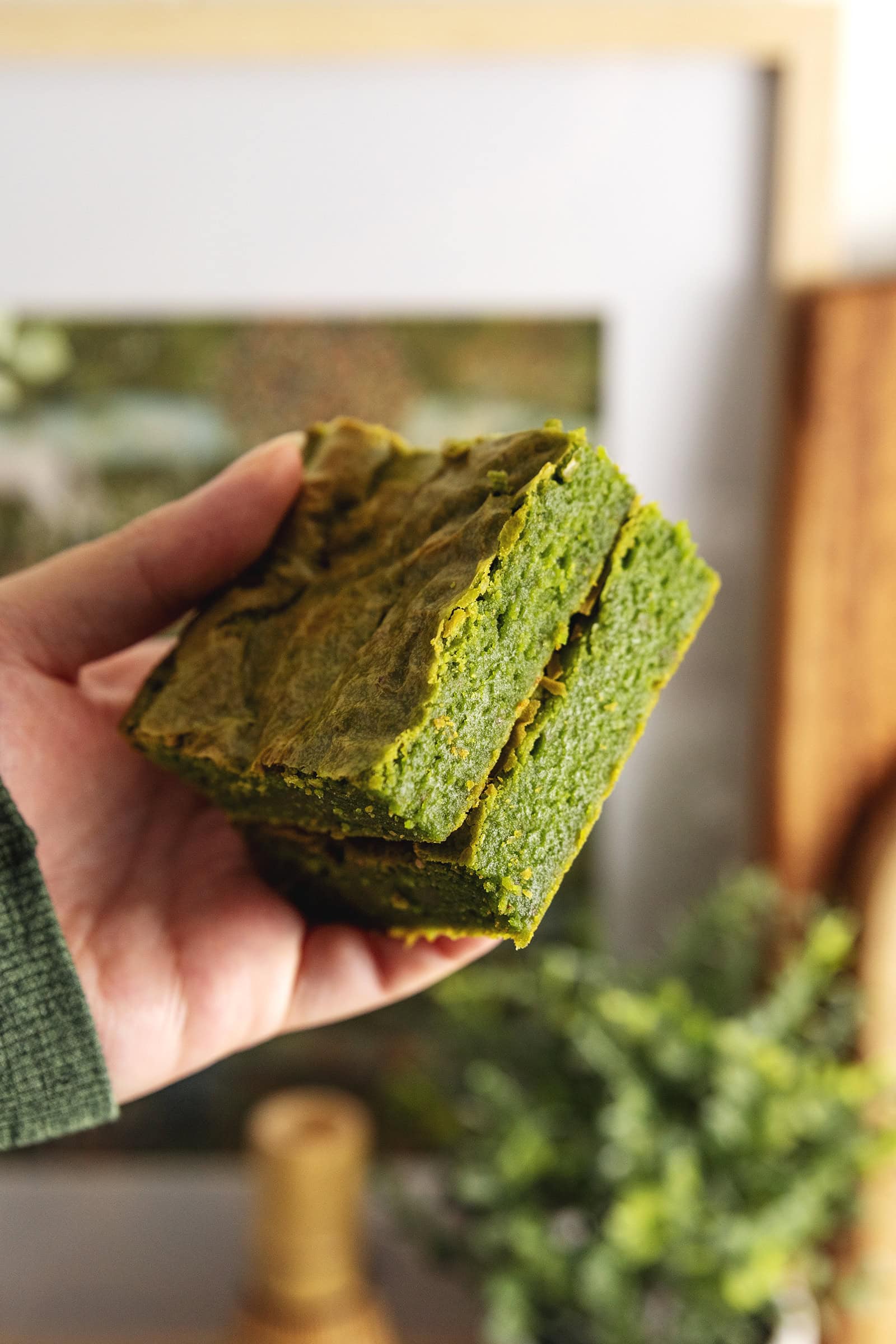 Hand holding two matcha brownies in a stack to show the texture.
