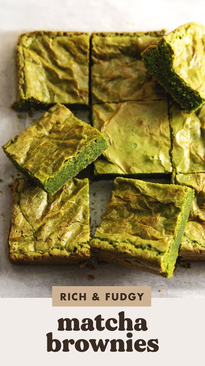 Matcha brownies on parchment paper with some brownies tilted and resting on the others.