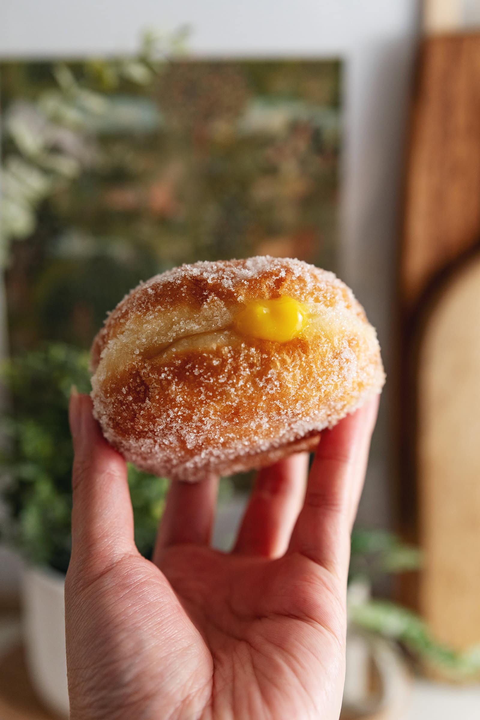 A hand holding a mango brioche donut.