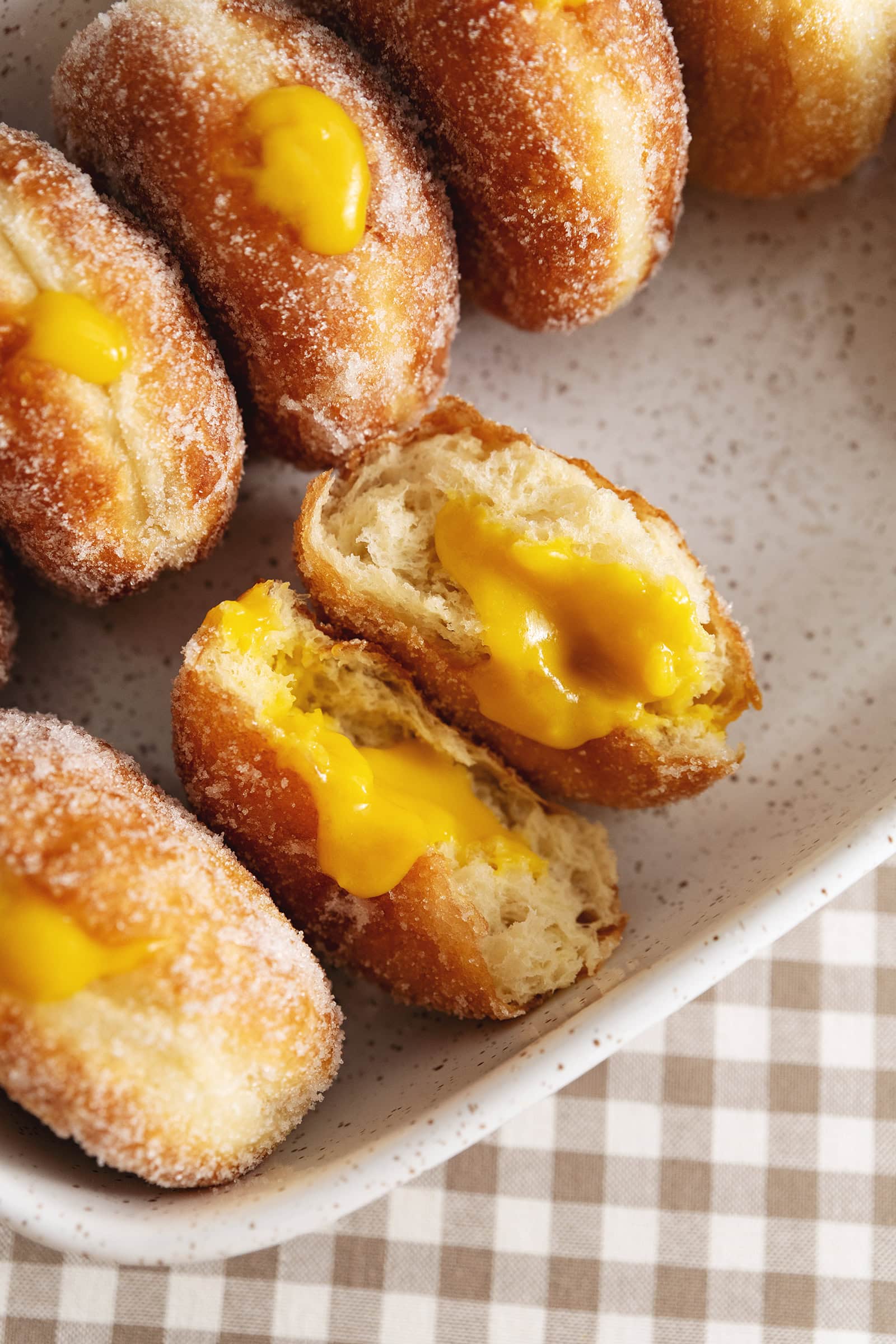 A mango brioche donut split in half to show the mango curd filling inside.