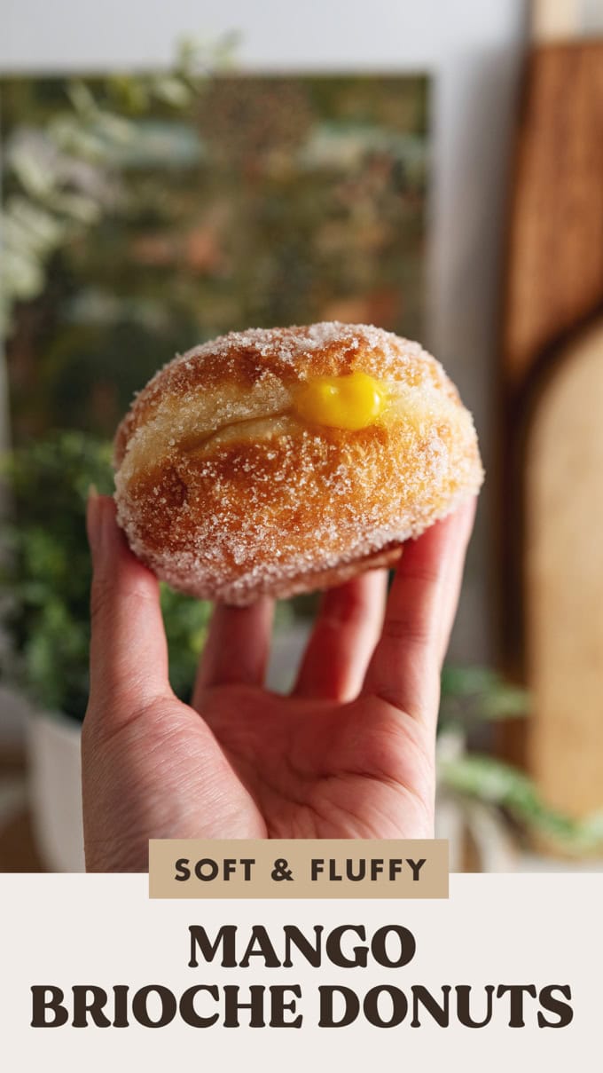 A hand holding a mango brioche donut.