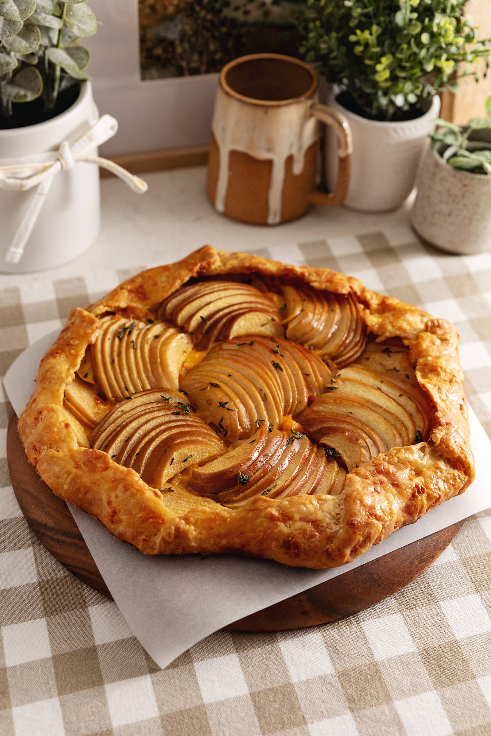 An apple cheddar galette on a wooden platter on a kitchen counter.