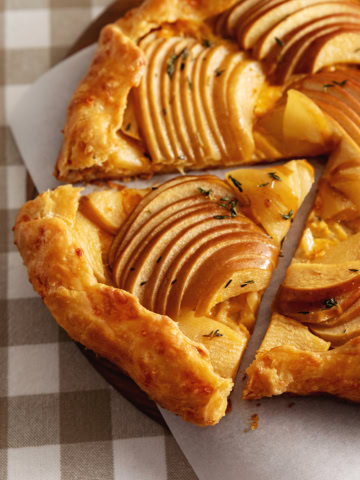 A triangular slice of an apple cheddar galette cut from the rest of the galette.