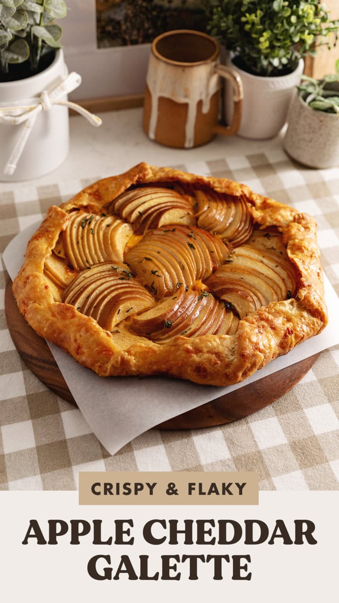 An apple cheddar galette on a wooden platter on a kitchen counter.