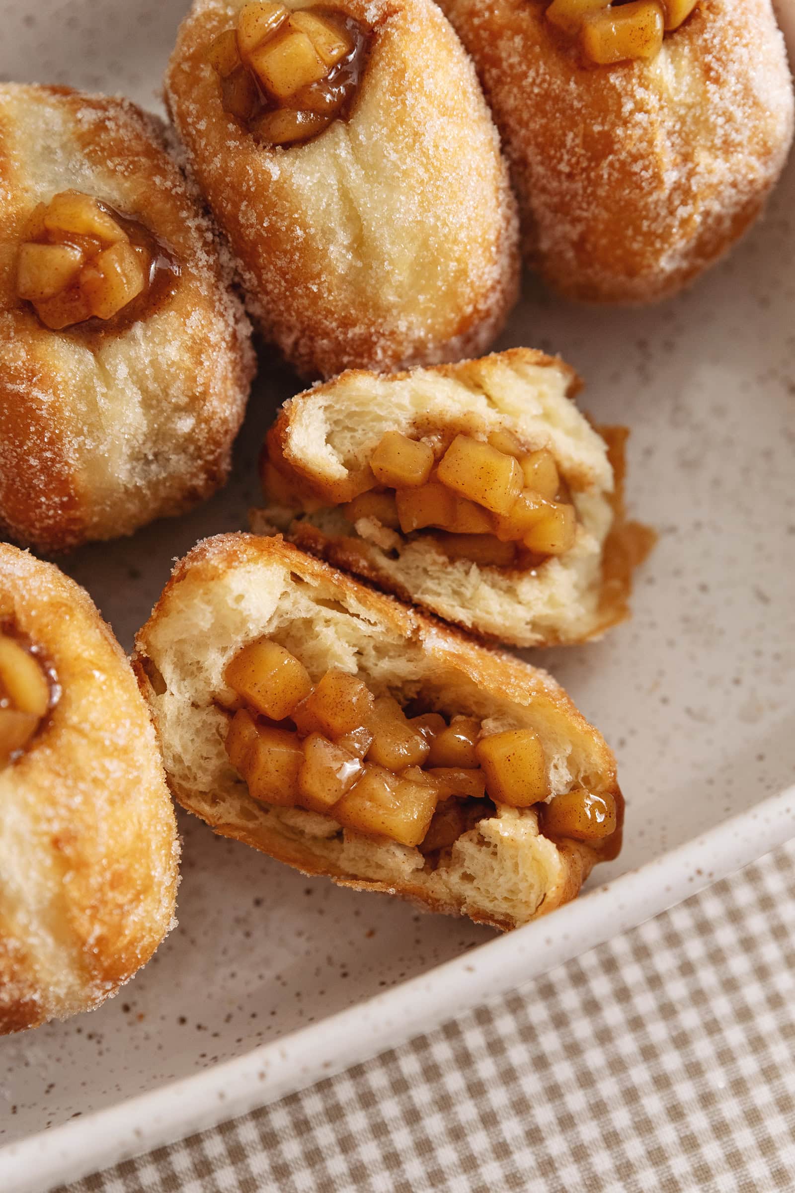 An apple pie donut ripped in half to show the apple pie filling inside.