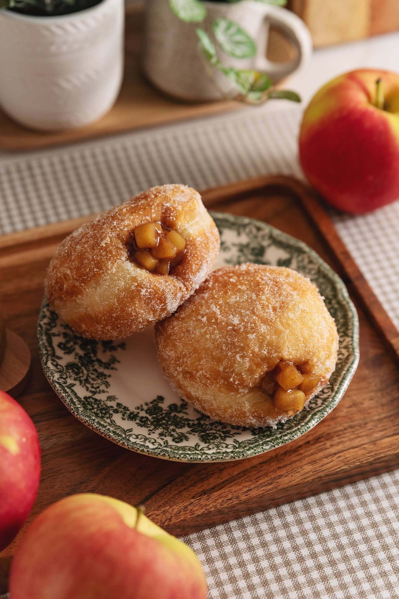 Two apple pie donuts on a plate on a wooden platter.