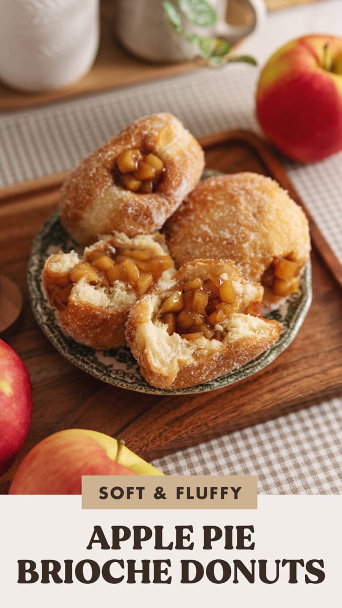 Two apple pie donuts on a plate and one donut ripped in half to show the apple pie filling inside.