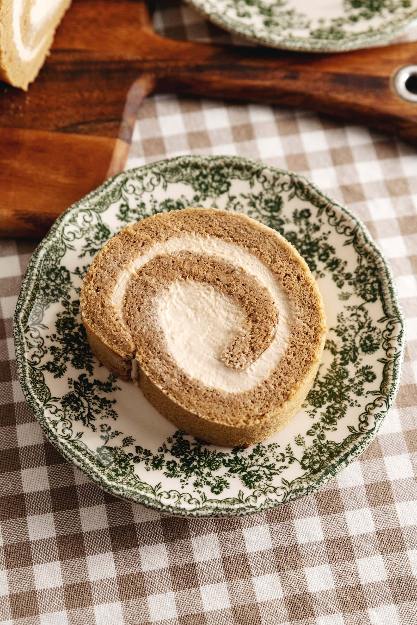 Top-down view of a slice of coffee swiss roll on a vintage plate.
