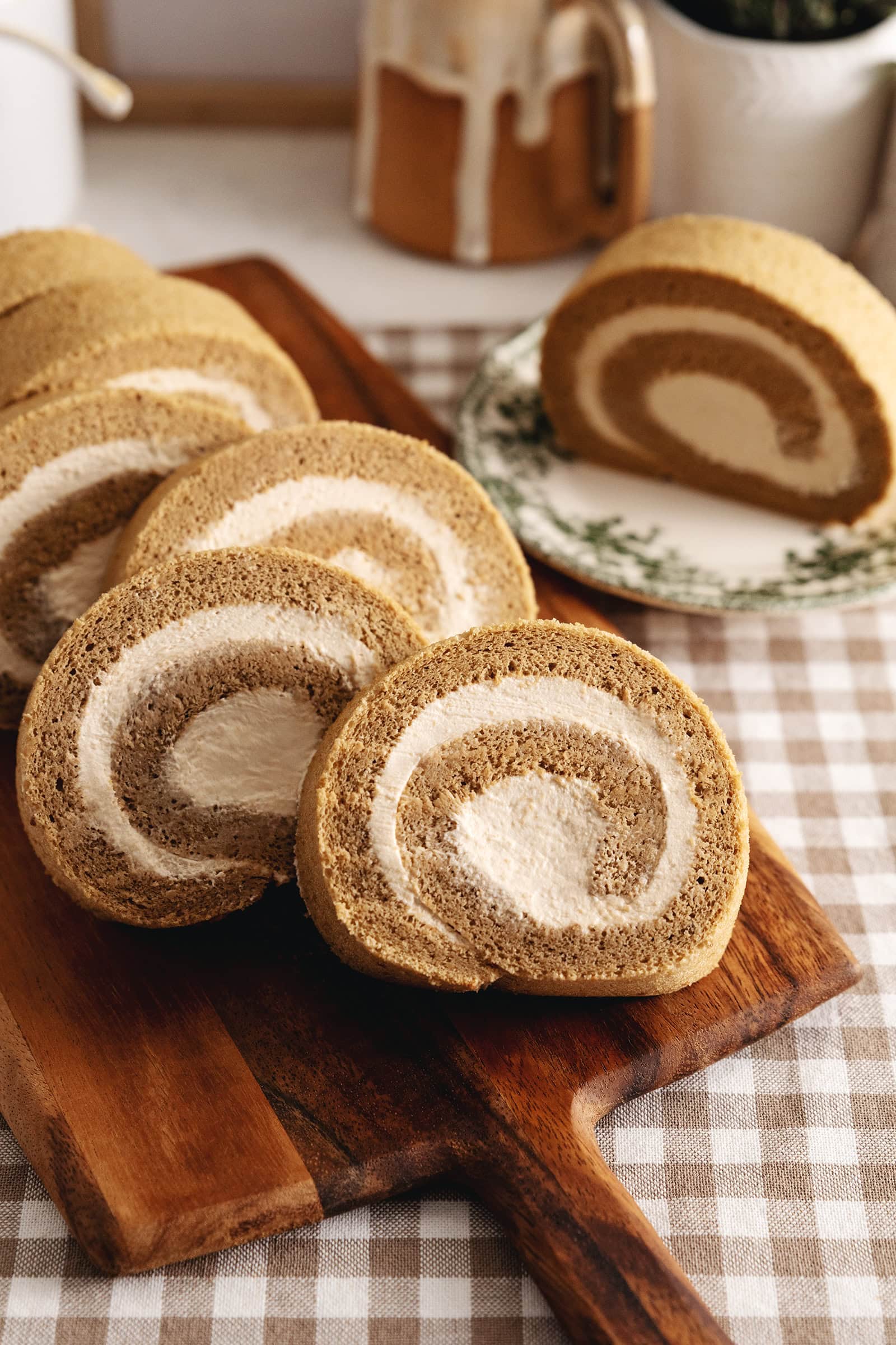 Several slices of a coffee swiss roll leaning against each other on a wooden board.