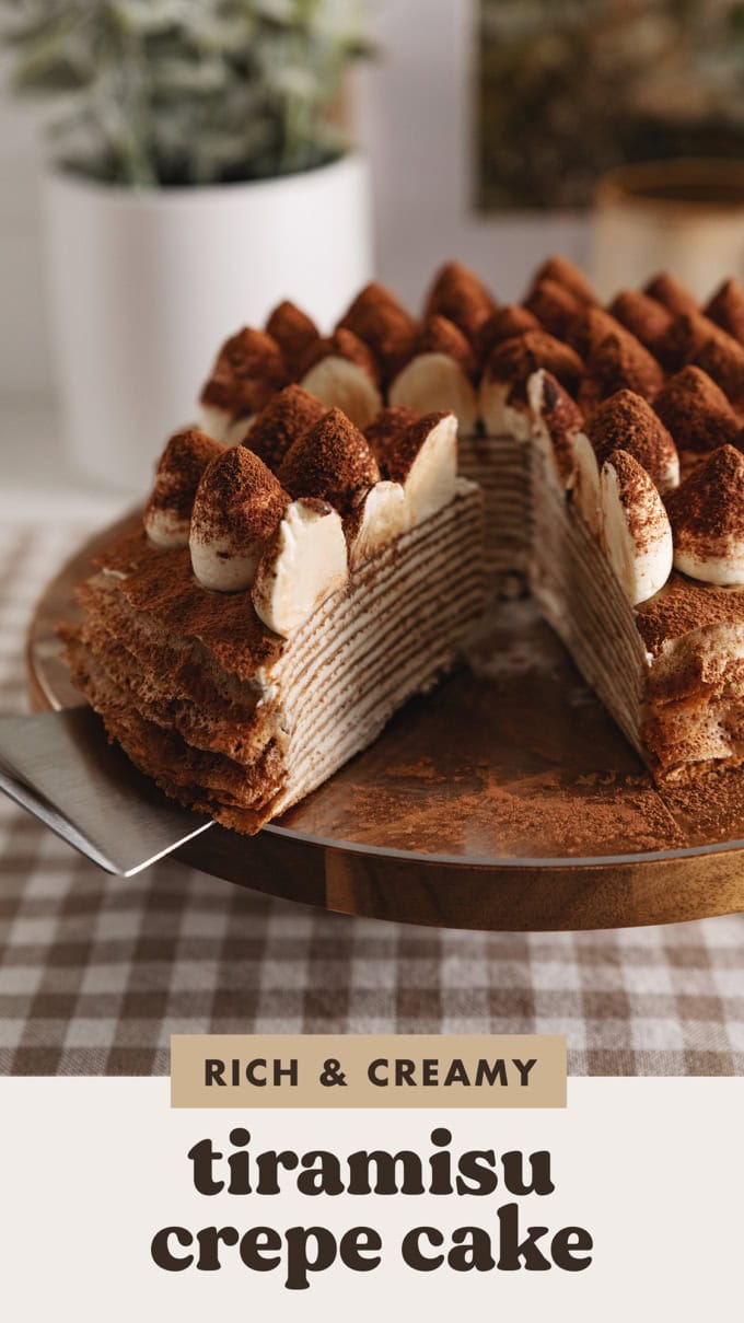 A slice of tiramisu crepe cake cut from the rest of the cake, sitting at an angle to show the crepe layers inside.