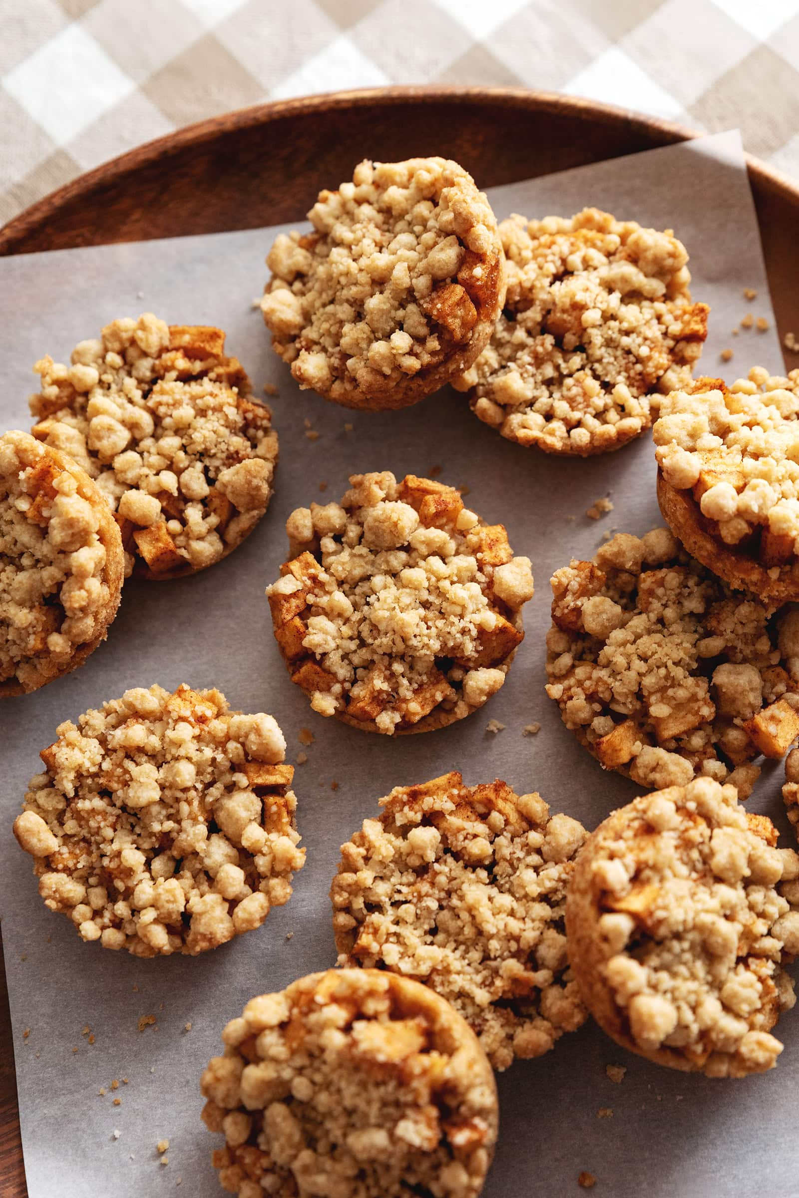 Apple crumble cookies scattered on a wooden platter.