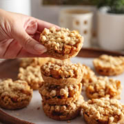 Hand holding an apple crumble cookie above a stack of cookies.
