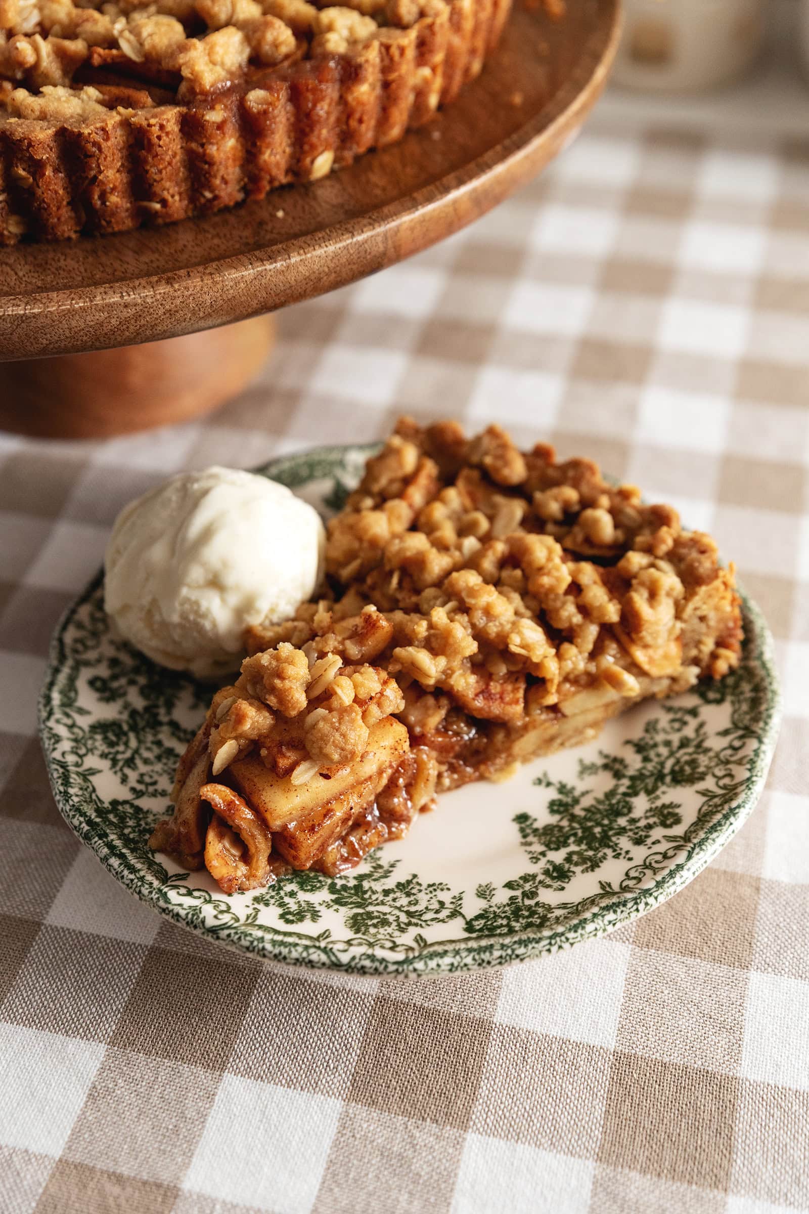 A slice of apple crumble tart and a scoop of ice cream on a vintage plate.
