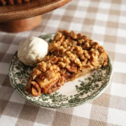 A slice of apple crumble tart and a scoop of ice cream on a vintage plate.
