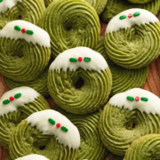 Several matcha butter cookies scattered and overlapping on a wooden tray.