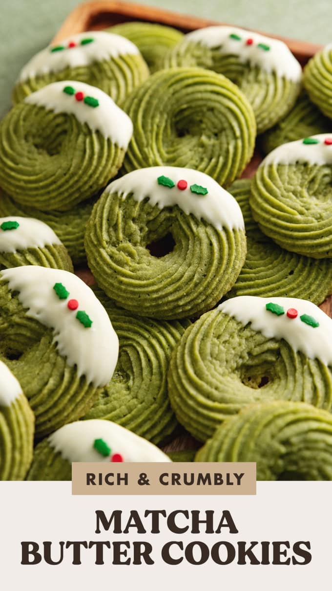Several matcha butter cookies decorated with Christmas sprinkles scattered and overlapping on a wooden tray.