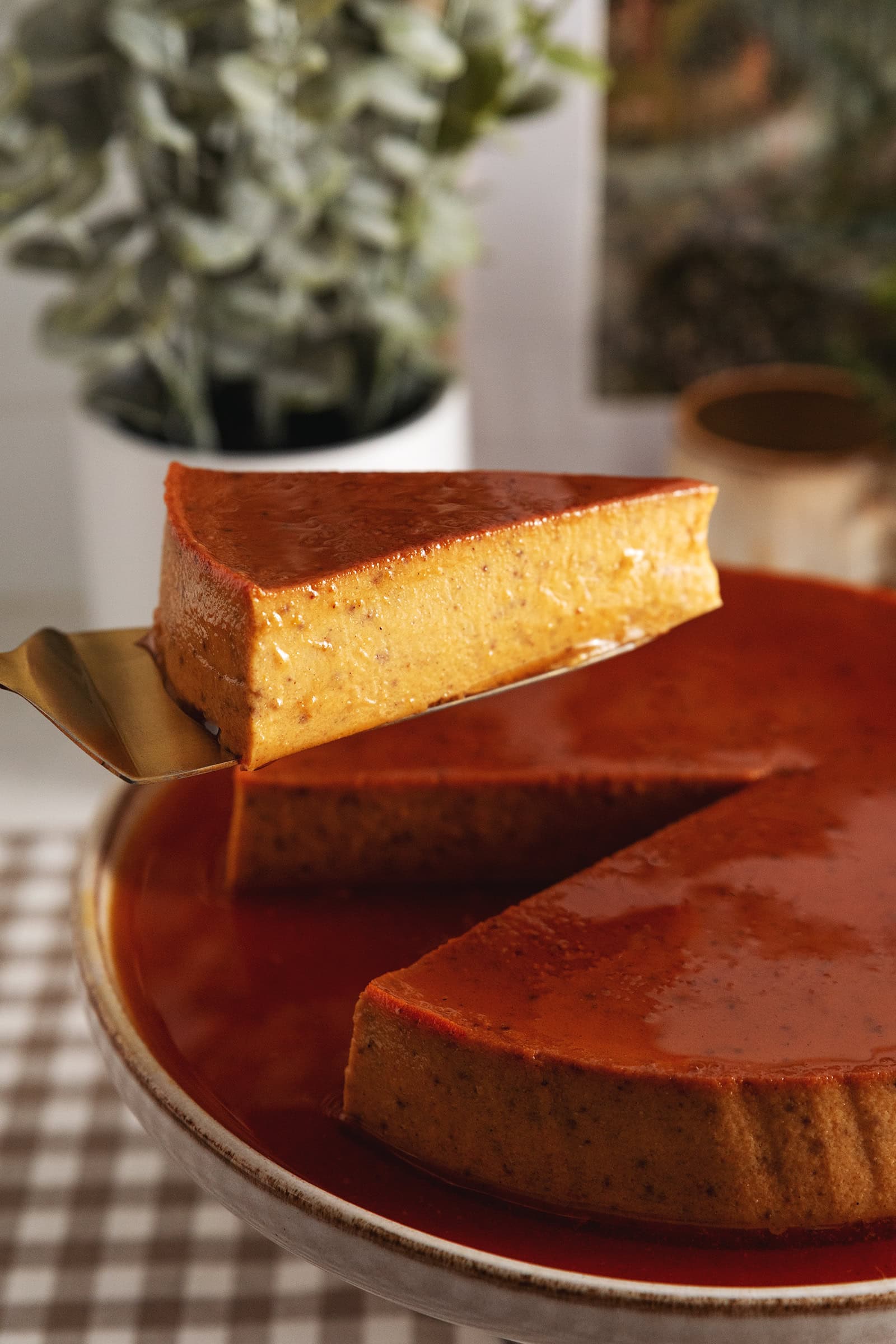A slice of pumpkin flan being lifted with a cake server above the rest of the flan.